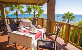 a dining table set up on a wooden deck overlooking the ocean , with multiple chairs surrounding it at Horus Paradise Luxury Resort - All Inclusive