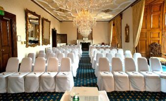 a large banquet hall with rows of chairs arranged in a symmetrical fashion , creating an intimate setting for an event at Dalhousie Castle Hotel