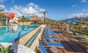 a large outdoor pool surrounded by lounge chairs and umbrellas , with a view of the ocean in the background at Margaritaville Vacation Club by Wyndham - St Thomas