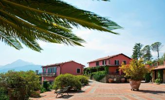 a red house with a balcony and palm trees in front of it , overlooking a city street at Renaissance Tuscany Il Ciocco Resort & Spa