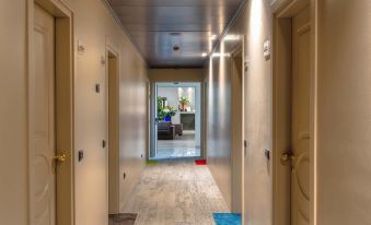 a hallway with a wooden floor and beige walls , leading to a room with a blue rug on the floor at Maranello Palace Hotel