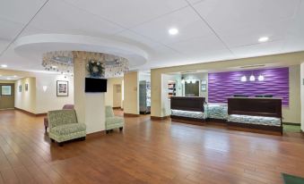 a spacious and well - lit hotel lobby with wooden floors , comfortable seating , and a reception desk at La Quinta Inn & Suites by Wyndham Springfield MA