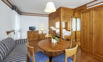 a modern living room with wooden furniture , including a dining table , chairs , and a couch at Grand Hotel Misurina