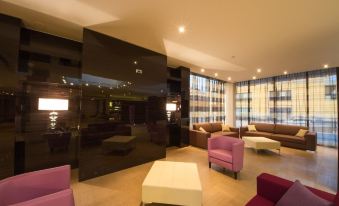 a modern living room with purple and white furniture , a large window , and a large screen on the wall at Quality Hotel Green Palace