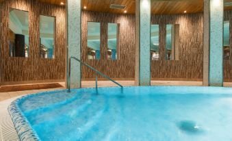 a large indoor swimming pool with wooden walls , a tiled floor , and a stone wall at Galaxy Hotel