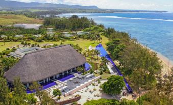 aerial view of a resort surrounded by water , featuring a pool , lounge chairs , and a lake at SO Sofitel Mauritius
