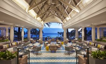 a large , open room with a high ceiling and columns , featuring a couch , chairs , and tables at Curacao Marriott Beach Resort