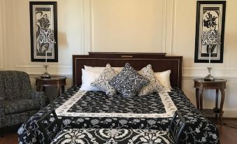 a black and white bedroom with a king - sized bed in the center of the room , surrounded by furniture and decorations at The Castle at Skylands Manor