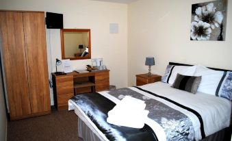 a modern hotel room with a bed , nightstands , and a desk , all decorated in neutral colors at The Village Inn