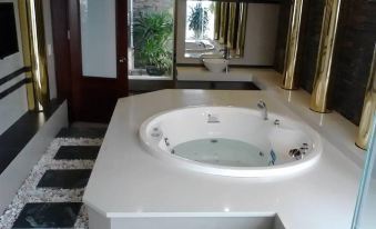 a luxurious bathroom with a large bathtub in the middle of the room , surrounded by white tiles and a mirror on the wall at Green Hotel