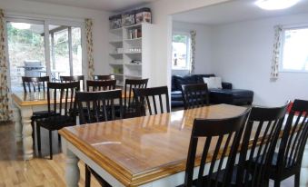 a dining room with a wooden table surrounded by black chairs and a bookshelf in the background at Tea Trees