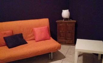 a cozy living room with an orange couch , a white coffee table , and a wooden cabinet at Buena Vista B&B