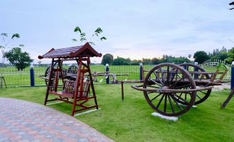 a wooden rocking chair and an antique wagon are displayed in a grassy field with benches at Infinity See Sun Resort