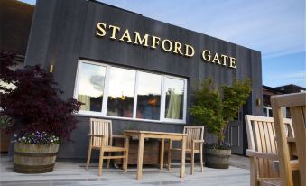 a restaurant with a large sign above the entrance , surrounded by wooden chairs and tables at Stamford Gate Hotel