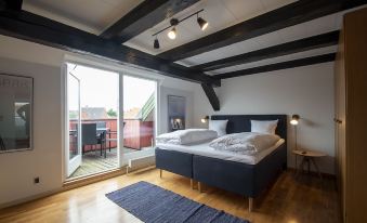 a modern bedroom with a large bed , wooden floors , and sliding glass doors leading to a balcony at Penthouse