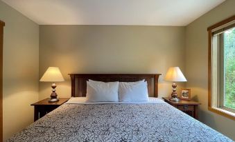 a bedroom with a large bed , two lamps on either side of the bed , and a lamp on the nightstand at Whispering Pines