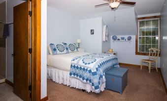 a cozy bedroom with a blue and white bed , a closet , and a ceiling fan at The Old Lantern Inn and Barn