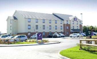 a large building with a purple sign in front of it and several cars parked outside at Premier Inn Herne Bay