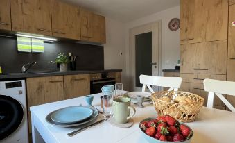 a kitchen with wooden cabinets , a white dining table , and a bowl of strawberries on the counter at Hartmann