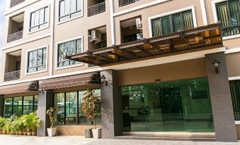 a modern building with an entrance and a glass door , surrounded by plants and trees at B2 Sriracha Premier Hotel