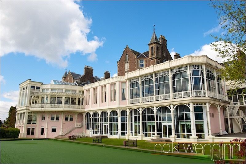 a large building with a green lawn and white columns , surrounded by tall windows and a fence at Crieff Hydro