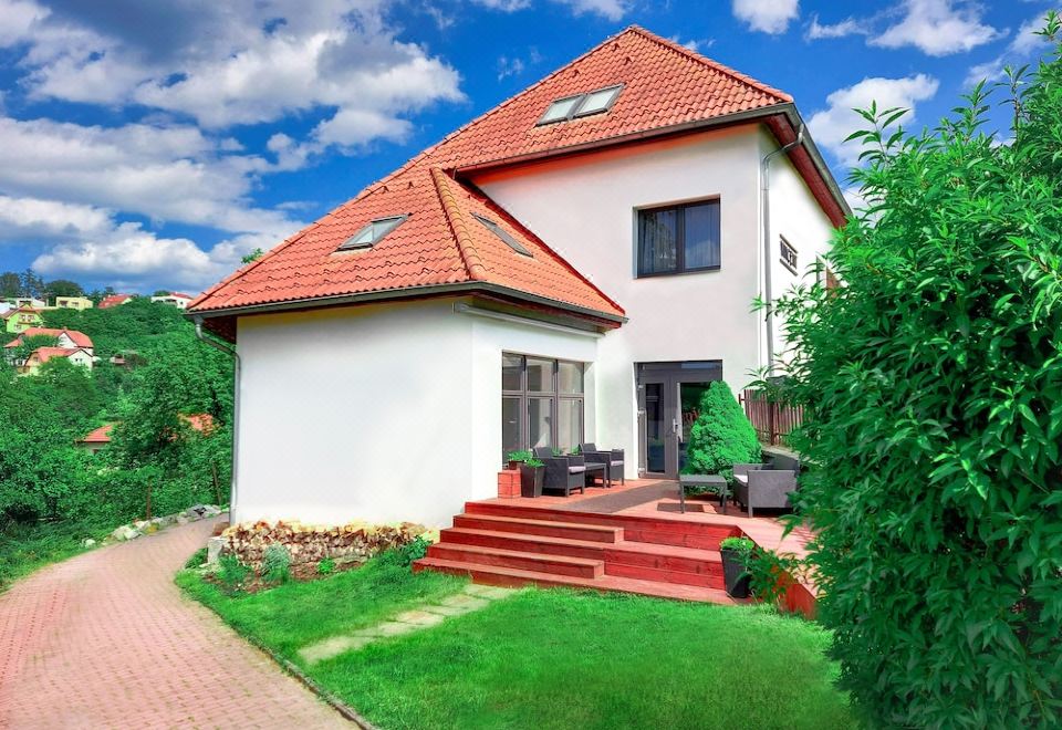 a two - story house with a red roof and white walls is surrounded by greenery and has a red - tiled roof at Vincent