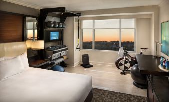a hotel room with a king - sized bed , a window with a view of the city , and various exercise equipment such as treadmills and at DoubleTree by Hilton Atlanta Airport