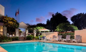 an outdoor pool surrounded by lounge chairs and umbrellas , with a sunset in the background at Four Points by Sheraton - San Francisco Bay Bridge