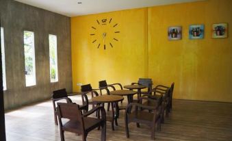 a room with a yellow wall and wooden floor has several tables and chairs arranged in a circle at Rimmueng Resort