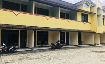 a row of three - story buildings with yellow walls and red accents , including a red door at Hotel Palapa