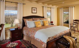 a large bed with a wooden headboard and floral bedding is situated in a bedroom with a rug on the floor at The Inn & Tavern at Meander
