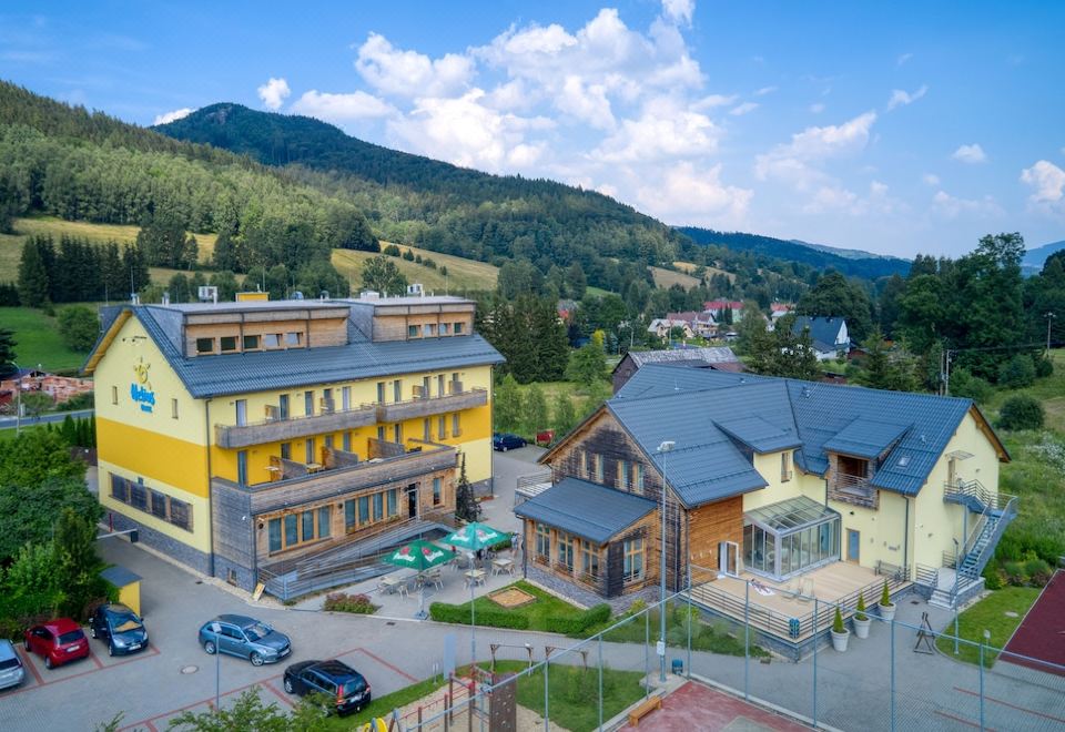 a large yellow building is situated in a rural area with mountains in the background at Hotel Helios