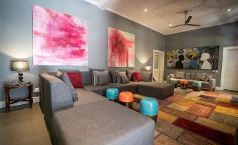 a modern living room with a large sectional couch , colorful ottomans , and a rug on the floor at Ruby Rose