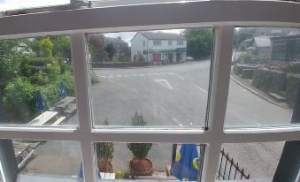 a view from a window shows a street with buildings and trees , with a white picket fence at The Engine Inn