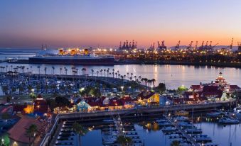 a harbor with a large ship docked in the harbor , surrounded by several boats and lit up at night at Hyatt Regency Long Beach