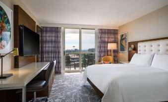 a hotel room with a king - sized bed , a desk , a chair , and a tv . the room also has a balcony overlooking the at Renaissance Meadowlands Hotel