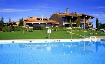 a large swimming pool is surrounded by grass and lounge chairs , with a building in the background at Parador de Santo Estevo