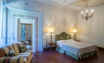 a luxurious hotel room with a large bed , white walls , and a chandelier , as well as a couch , table , and lamp at Hotel Villa Sermolli