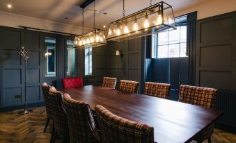 a large wooden dining table surrounded by plaid chairs in a room with dark wood paneling at The Seafield Arms-Cullen