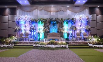 a stage set up for a wedding reception , adorned with flowers and lights , creating a festive atmosphere at Hotel Horison Gkb Gresik