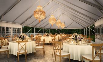 a large white tent with tables and chairs set up for a wedding reception , surrounded by chandeliers and flowers at Tailwater Lodge Altmar, Tapestry Collection by Hilton