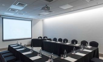 a conference room set up for a meeting , with chairs arranged in rows and a projector on the wall at Icon Hotel