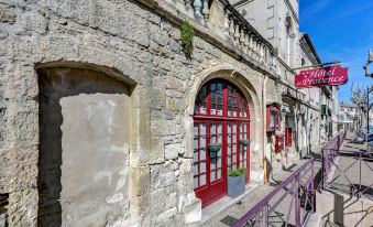 a red door is decorated with plants and sits on the side of a stone building at Hotel des Artistes