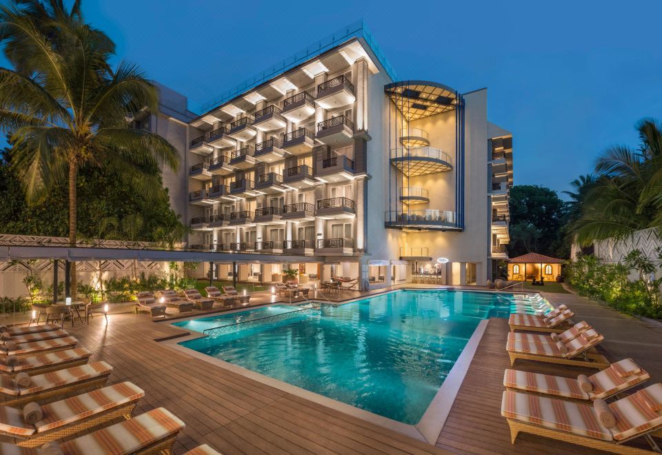a modern hotel with a large swimming pool surrounded by wooden decking , providing a relaxing atmosphere for guests at Le Meridien Goa, Calangute