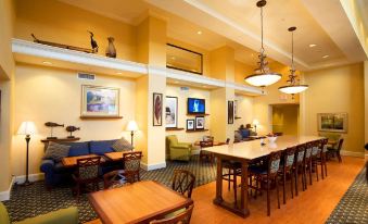 a well - lit hotel lobby with multiple couches , chairs , and tables arranged for guests to relax and socialize at Hampton Inn & Suites Lake Wales