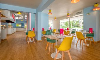 a brightly colored restaurant with wooden floors and chairs , dining tables , and a bar area at Allegro Agadir