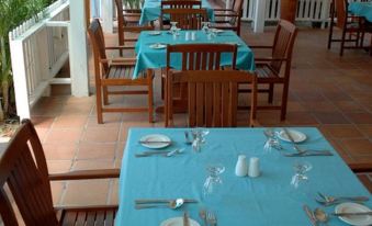 a restaurant with wooden tables and chairs , blue tablecloths , and white plates on each table at Anchorage Inn