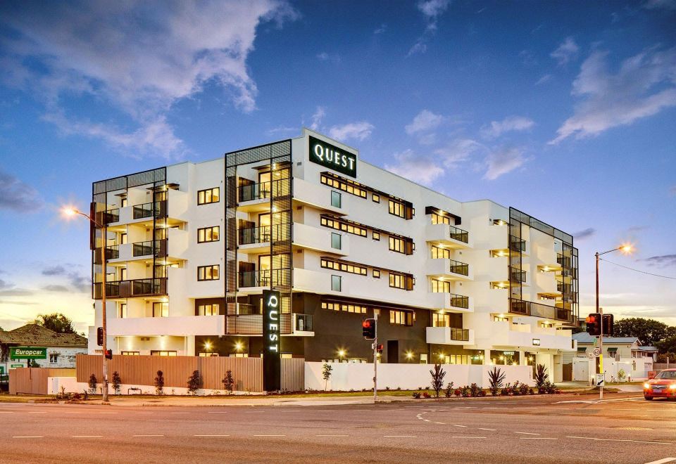 "a large building with a green sign that says "" quest "" in front of it , under a blue sky" at Quest Cannon Hill