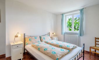 a white bedroom with a double bed , two nightstands , and a window with a view of trees at Federica