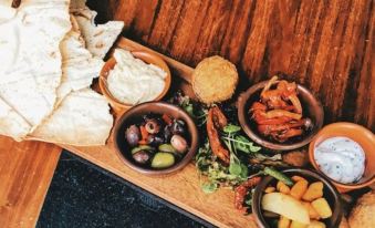 a wooden platter with various dishes , including olives and cheese , on a black marble table at The George at Baldock